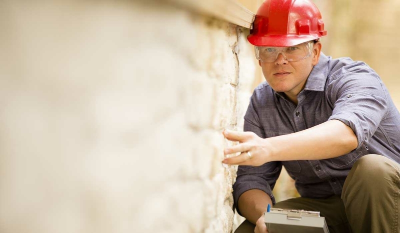 Insurance adjuster inspecting a damaged stone wall