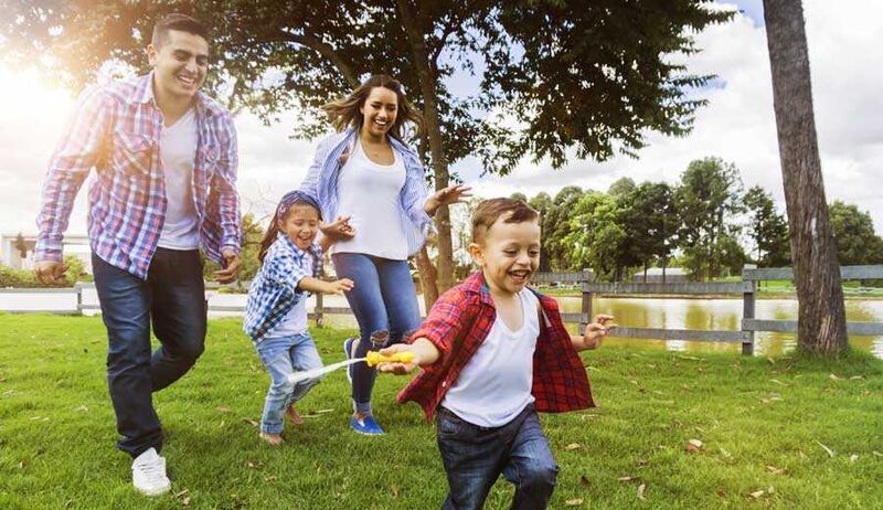 Family laughing as they run through a park