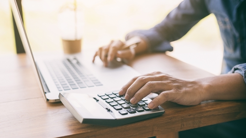 Man working on computer and calculator